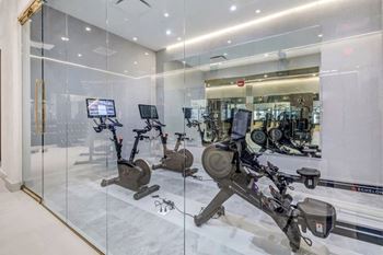 a gym with cardio equipment and glass walls